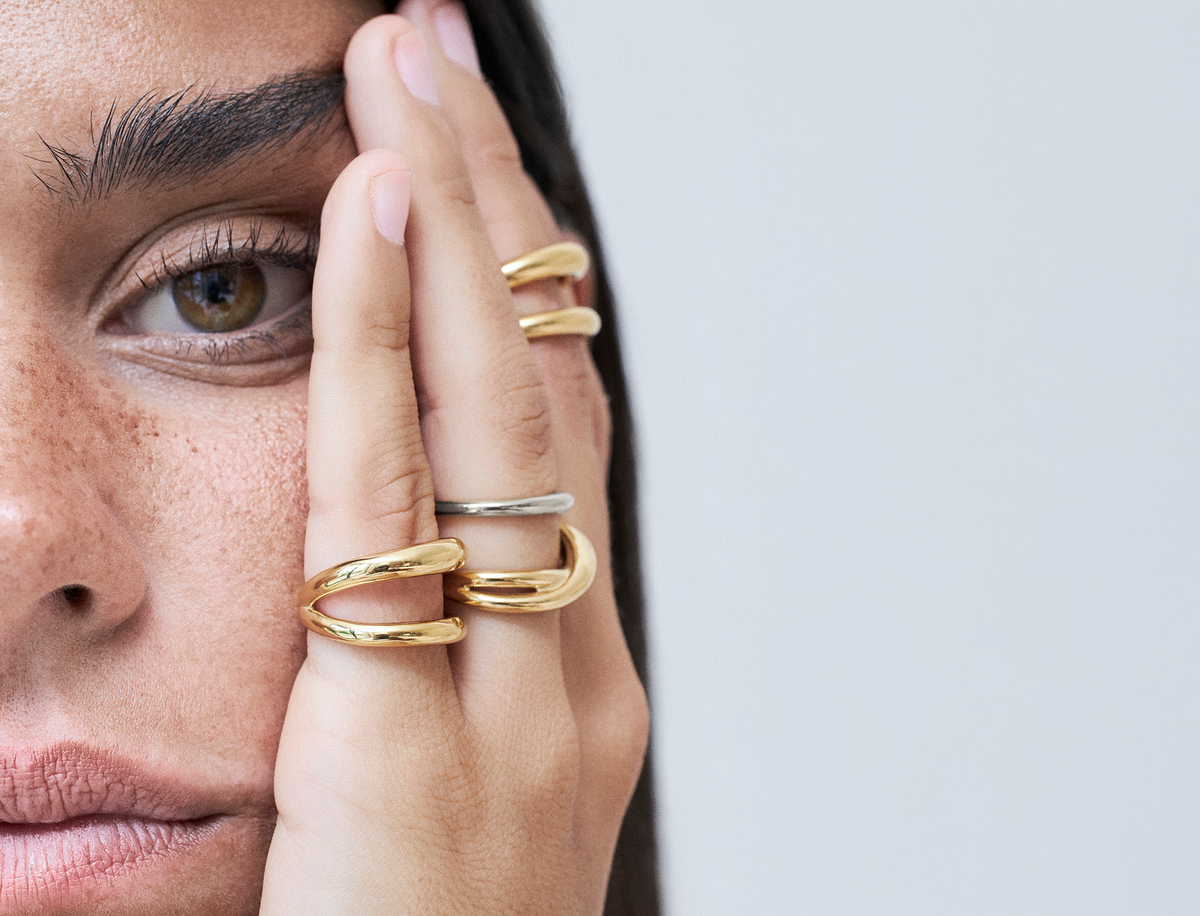 Mixing silver and gold jewelry styles with elegant rings on a model's hand.
