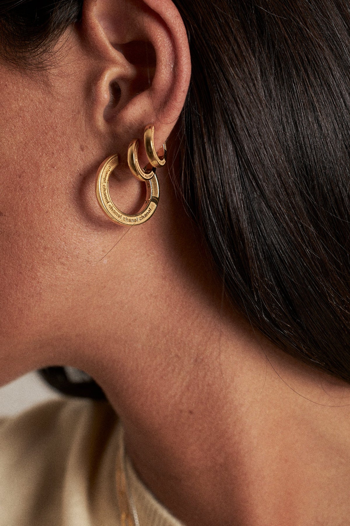 Close-up of a woman's ear adorned with golden feminine huggies vs hoops earrings, showcasing style and elegance.