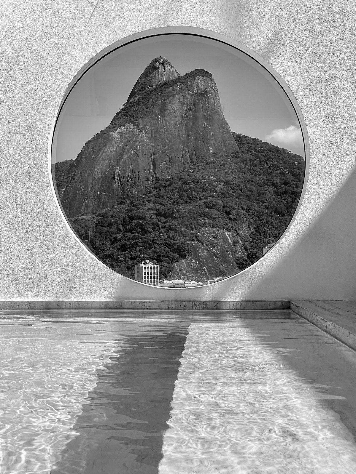 Scenic view of a mountain through a circular window with water reflections, Rio de Janeiro travel tips.