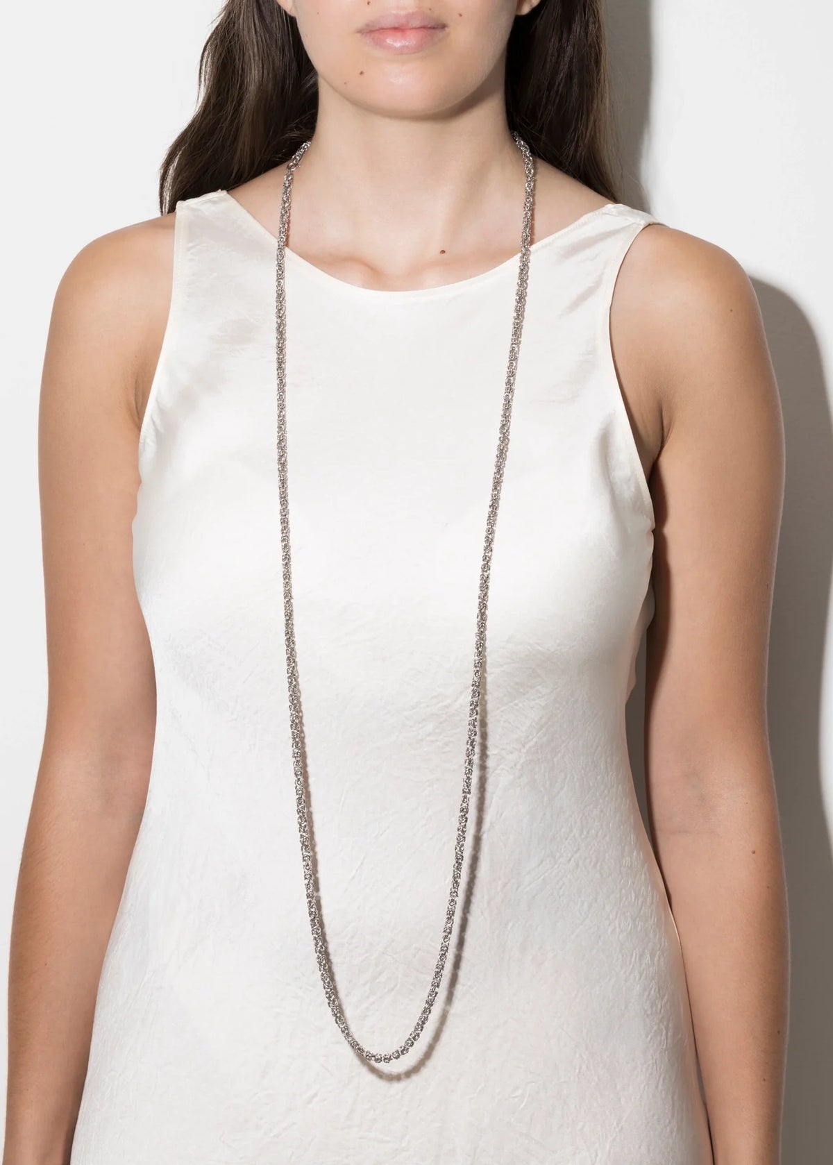 Fashionable 925 silver jewelry review: woman wearing a long silver chain necklace with a simple dress.