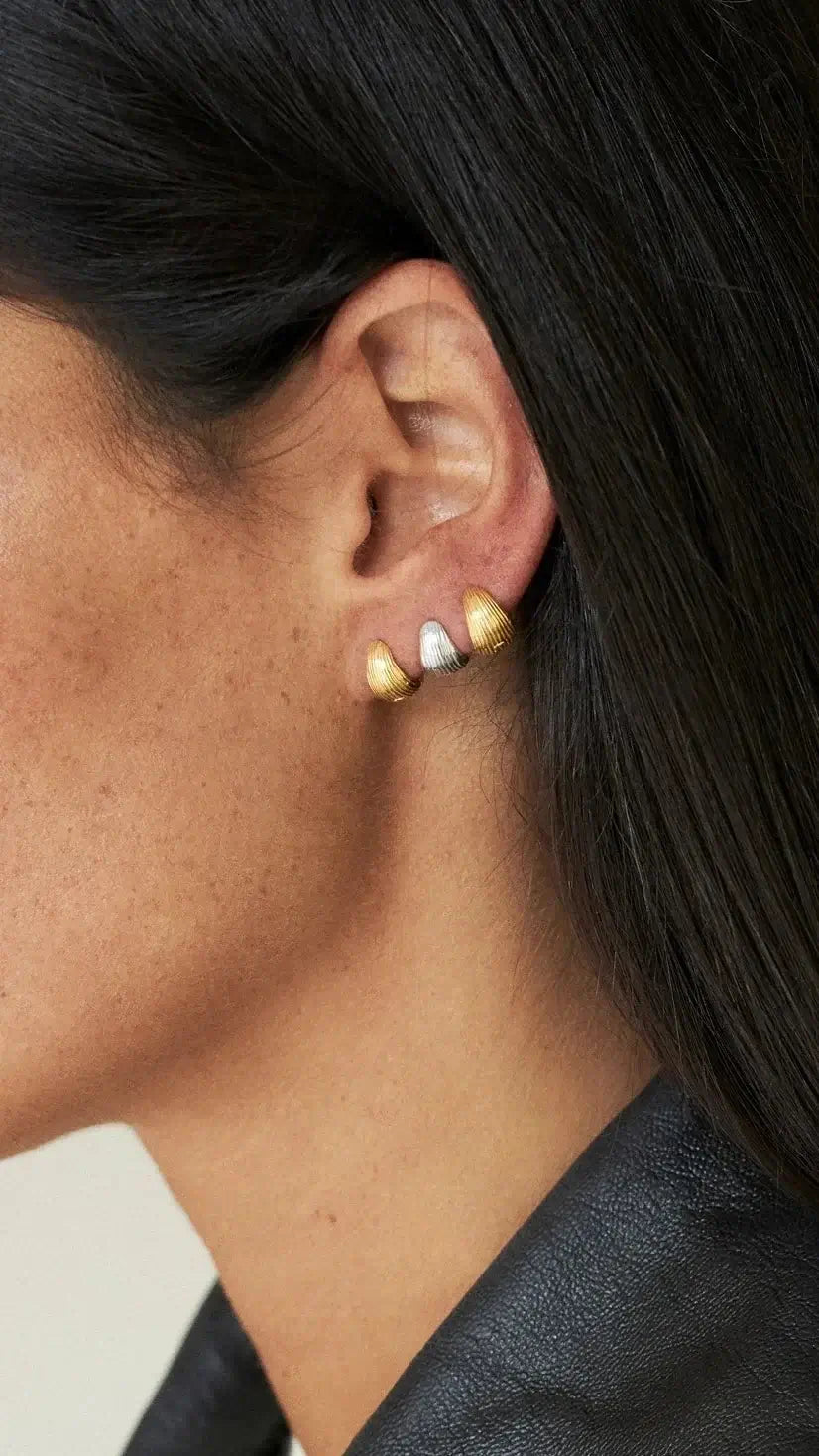Tilly huggie earrings silver gold worn on a woman's ear, showcasing gold and silver plating, elegant and stylish.