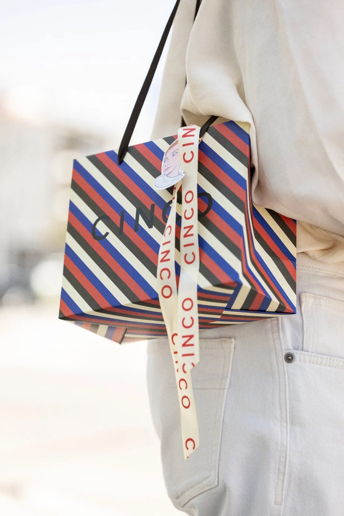Colar inicial para presente elegantly wrapped in a stylish bag with colorful stripes and a decorative ribbon.