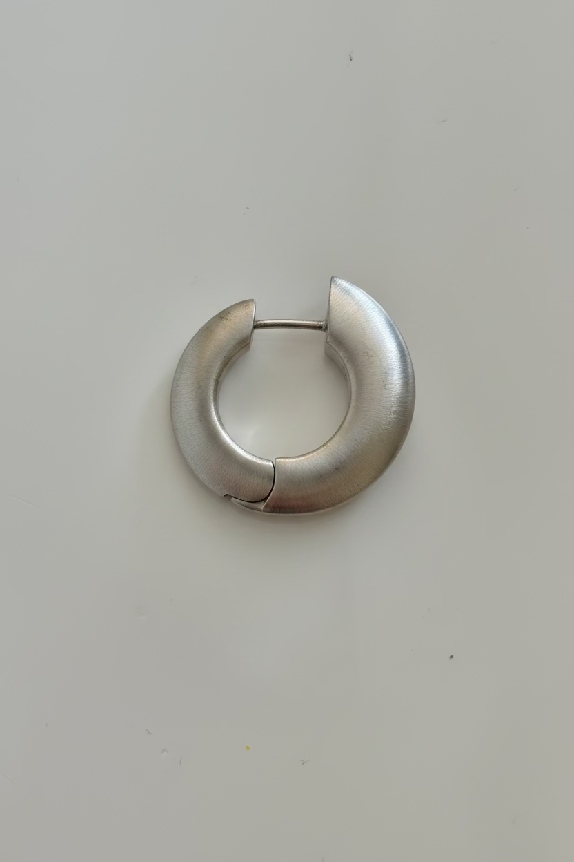 A single gold crescent-shaped hoop earring with a matte finish, shown on a plain light gray background.