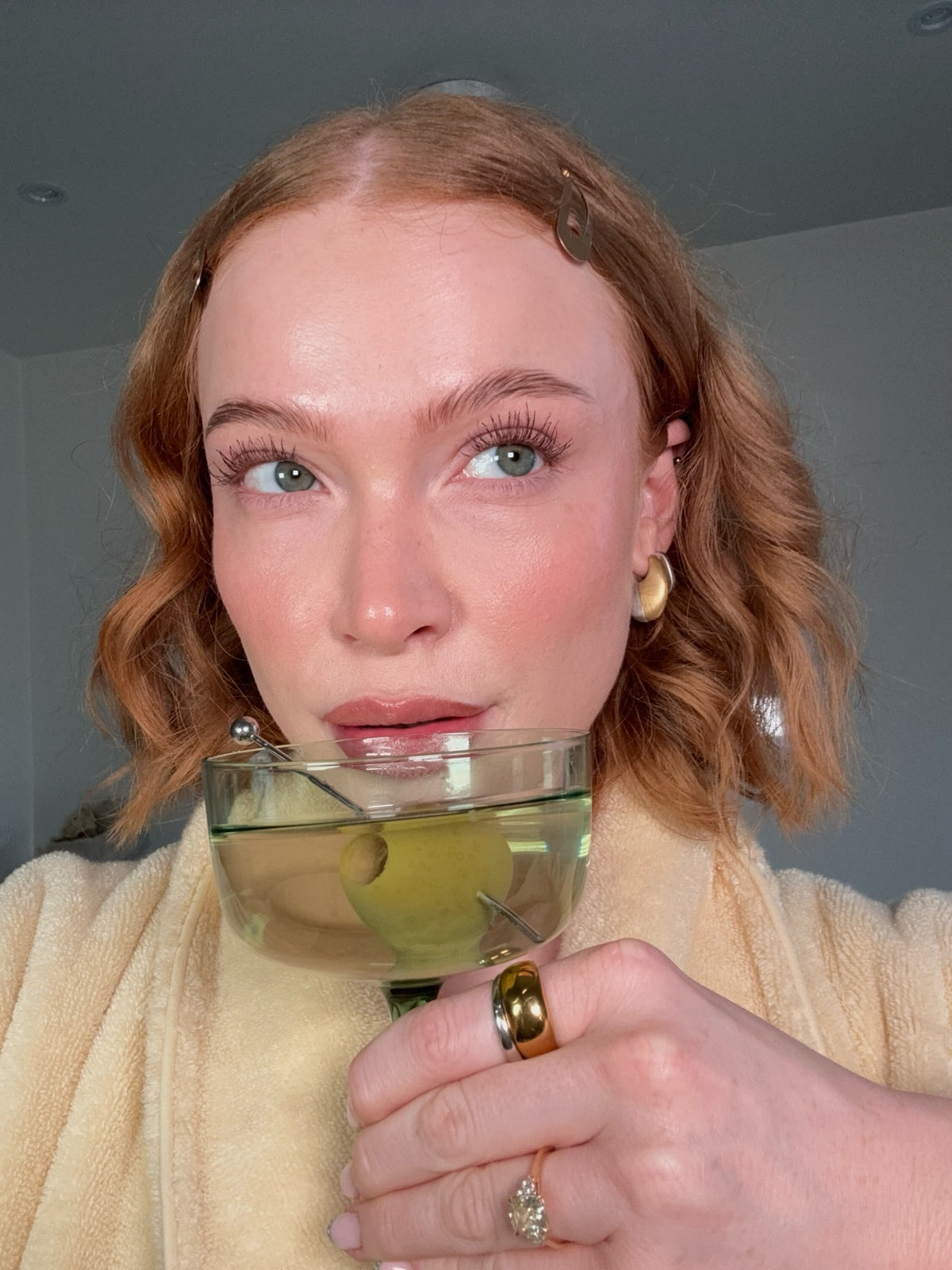 CINCO jewelry model holding a cocktail with an olive while wearing gold earrings and rings.