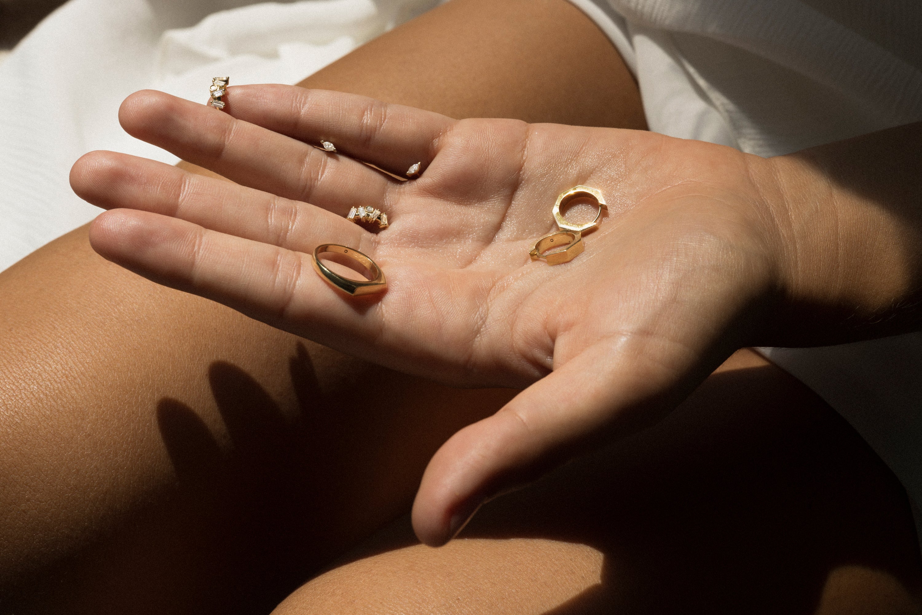 Hand holding three gold rings with a neutral background