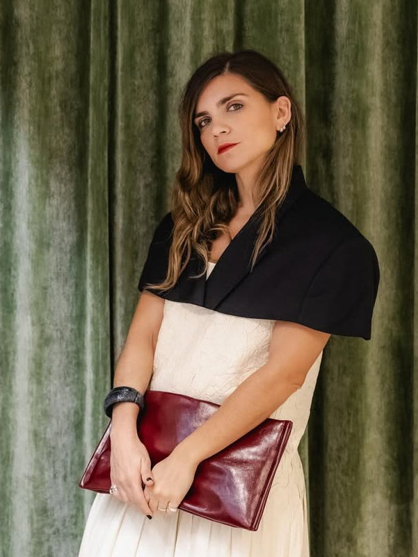 Woman holding a red clutch against a green curtain background