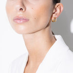 model wearing lizzie earrings and amina huggies white in gold